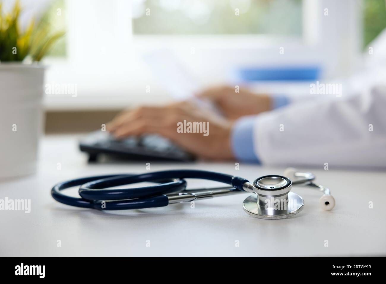 stethoscope on the table in clinic office. doctor working on computer in background Stock Photo