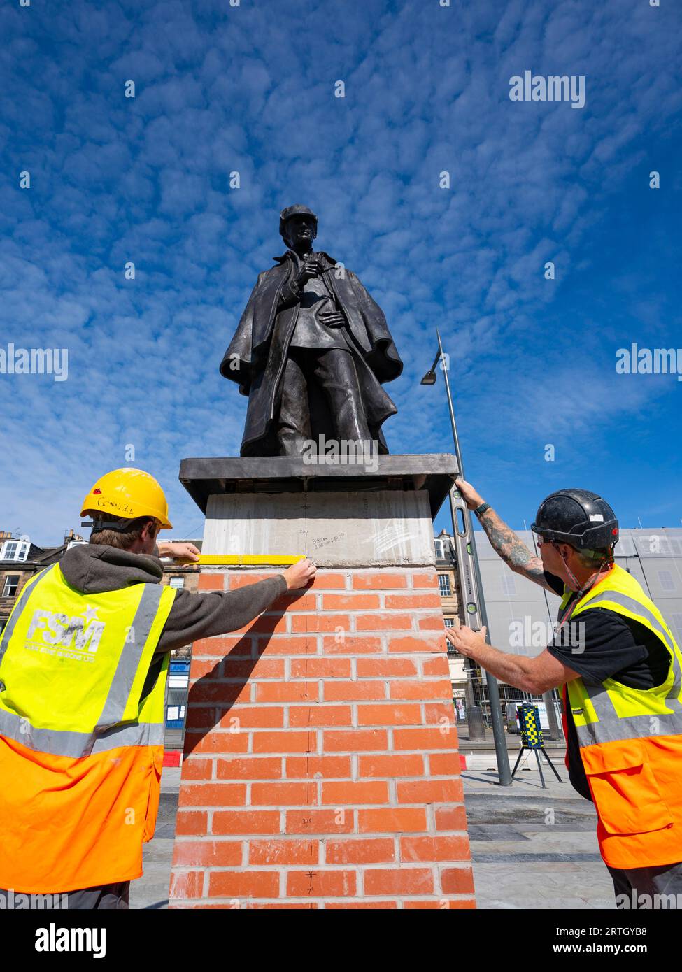 Edinburgh, Scotland, UK. 9th September 2023.  Newly refurbished statue of Sherlock Holmes unveiled today at new location on Picardy Place by Sir Arthur Conan Doyle’s relative Tania Henzell and Transport Convener, Councillor Scott Arthur. Marking the nearby birthplace of the super sleuth’s creator, Sir Arthur Conan Doyle, the life-sized bronze sculpture was removed in 2018 while Trams to Newhaven works were carried out. It has been renovated by Black Isle Bronze in Nairn. PIC; Workmen make finishing touches to plinth holding the statue.  Iain Masterton/Alamy Live News Stock Photo