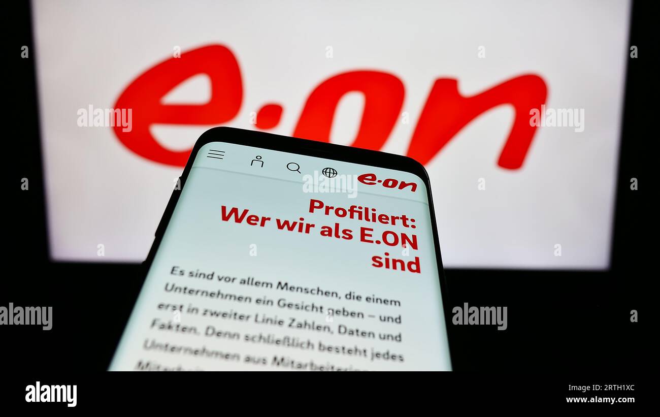 Mobile phone with webpage of German energy company E.ON SE on screen in front of business logo. Focus on top-left of phone display. Stock Photo