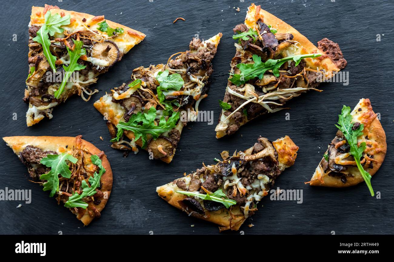 Top down view of slices of mushroom beef flatbread pizza on a slate