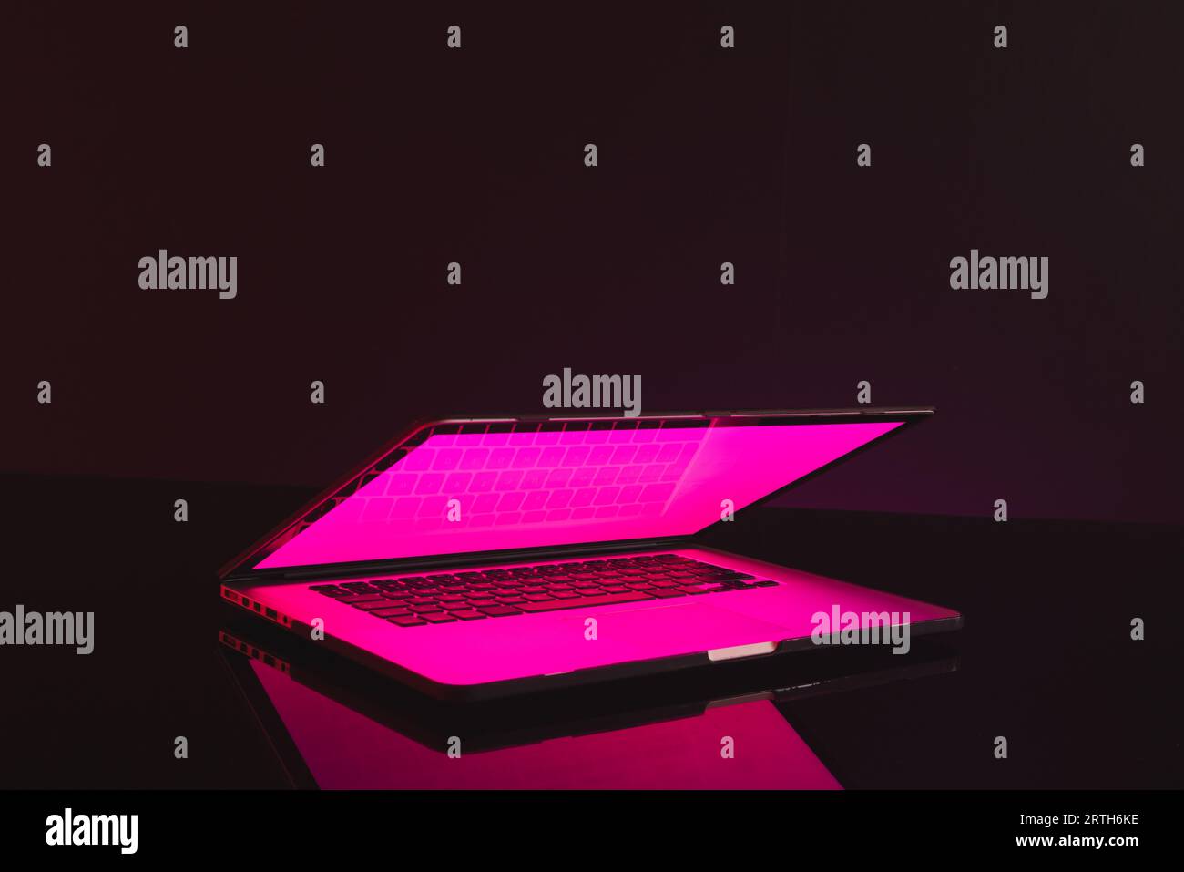 Composite of laptop with glowing screen and copy space on neon background Stock Photo