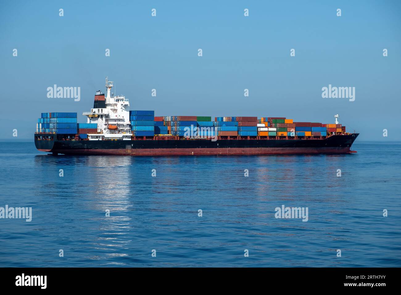 Container cargo ship loaded moored in open Mediterranean sea, Piraeus port Greece. Storage and carry of heavy merchandise for import, export. Stock Photo