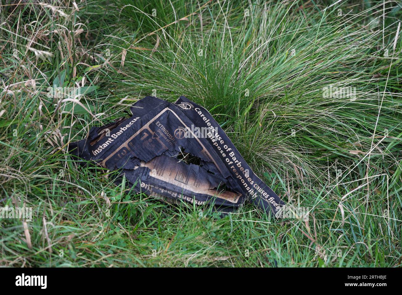 Irresponsibly dumped burned disposable barbeque packaging with warnings that have been ignored, Teasdale, County Durham, UK Stock Photo