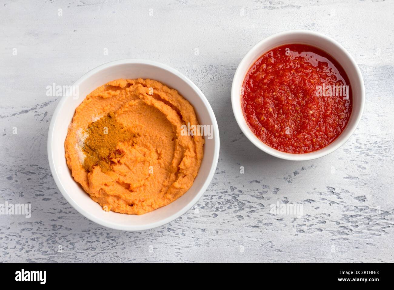 Ingredients for homemade lentil pancakes: fresh tomato sauce with spices, ground red lentils and spices -turmeric, paprika, salt on a light gray backg Stock Photo