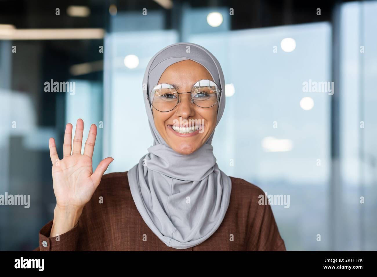 Portrait of a young Muslim woman in a hijab sitting in the office and ...