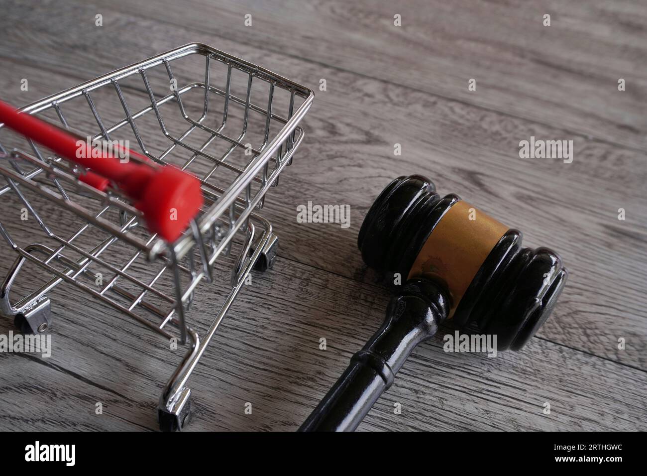 Closeup image of judge gavel and shopping trolley on table. Consumer rights, customer protection, commercial law concept Stock Photo