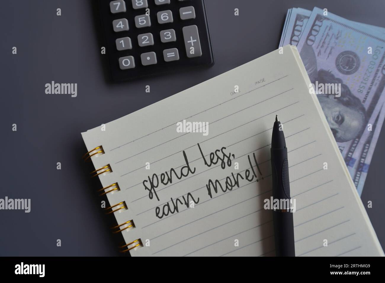 Top view image of money, calculator and notebook with text SPEND LESS, EARN MORE!!. Financial concept Stock Photo