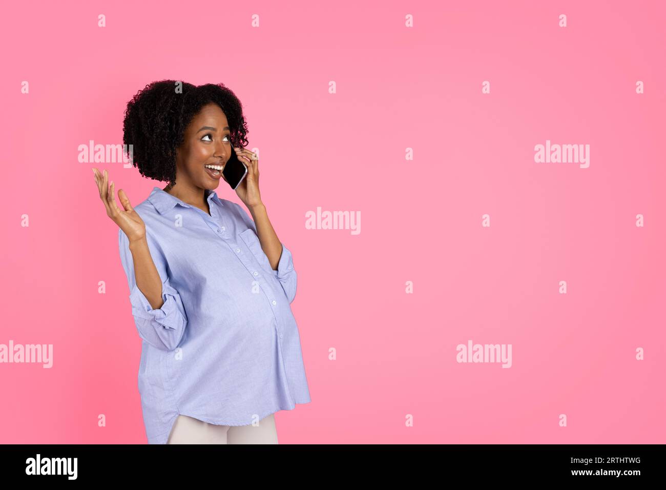 Shocked cheerful millennial black lady with big belly calling by phone, speaking Stock Photo