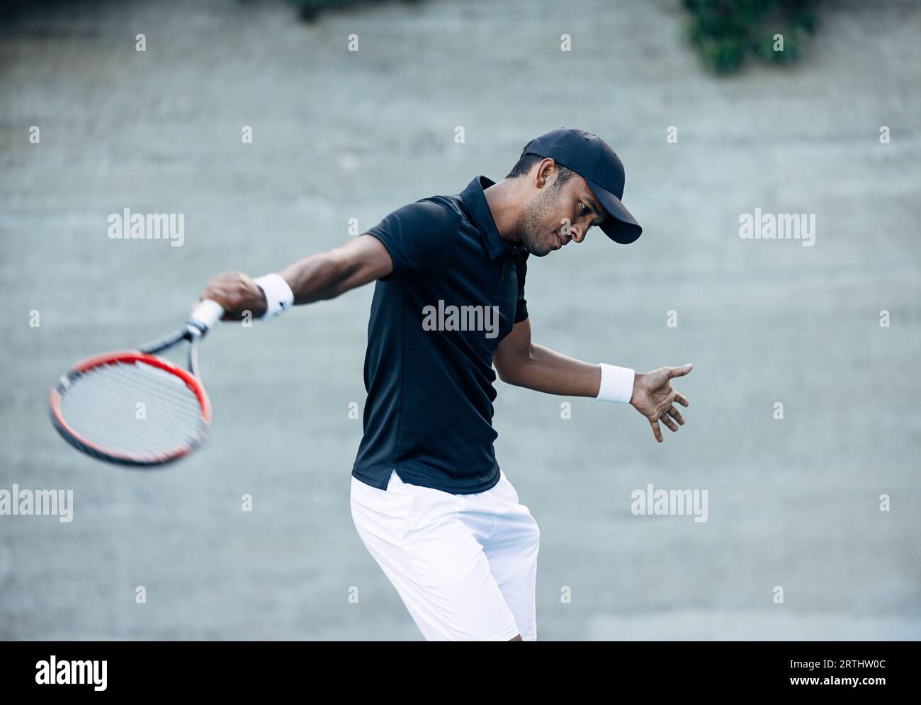 Male tennis player practicing hit outdoors. Professional tennis player spending time on a hard court. Stock Photo