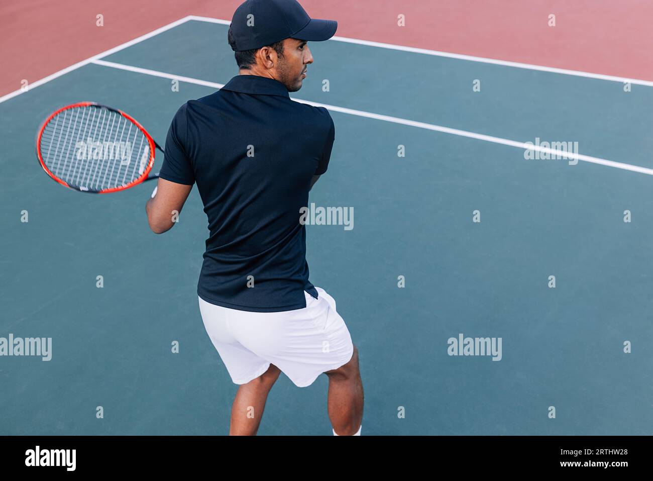 Back view of a male tennis player practicing a hard court outdoors Stock Photo