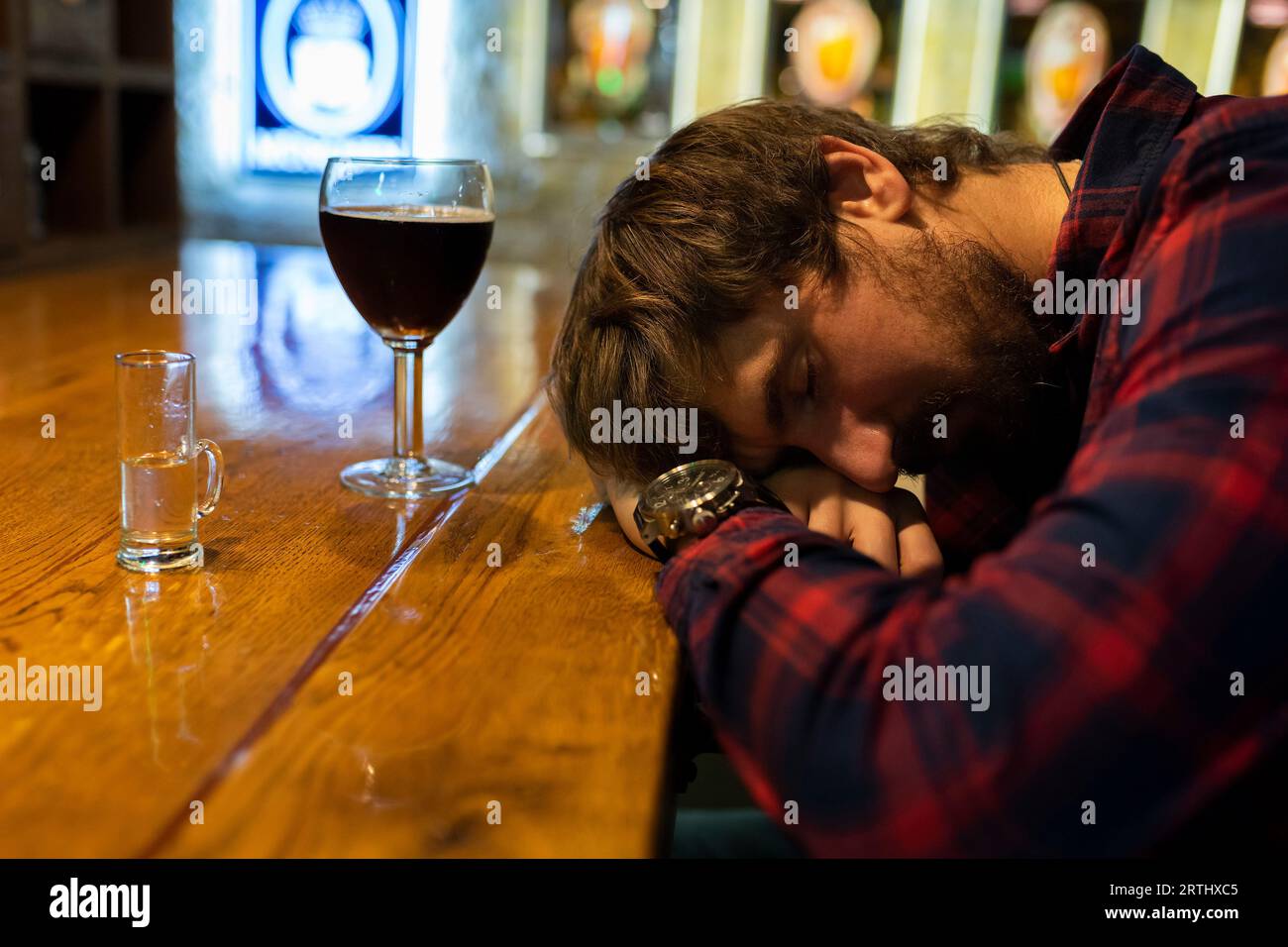 A drunk young man is sleeping on a bar counter in a bar. Alcohol