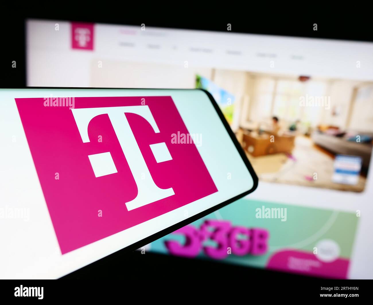Mobile phone with logo of telecommunications company Deutsche Telekom AG on screen in front of website. Focus on center of phone display. Stock Photo