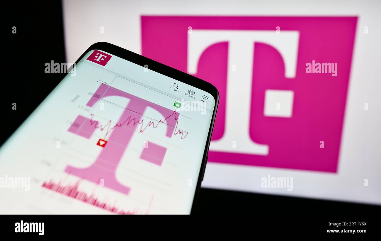 Smartphone with website of telecommunications company Deutsche Telekom AG on screen in front of logo. Focus on top-left of phone display. Stock Photo