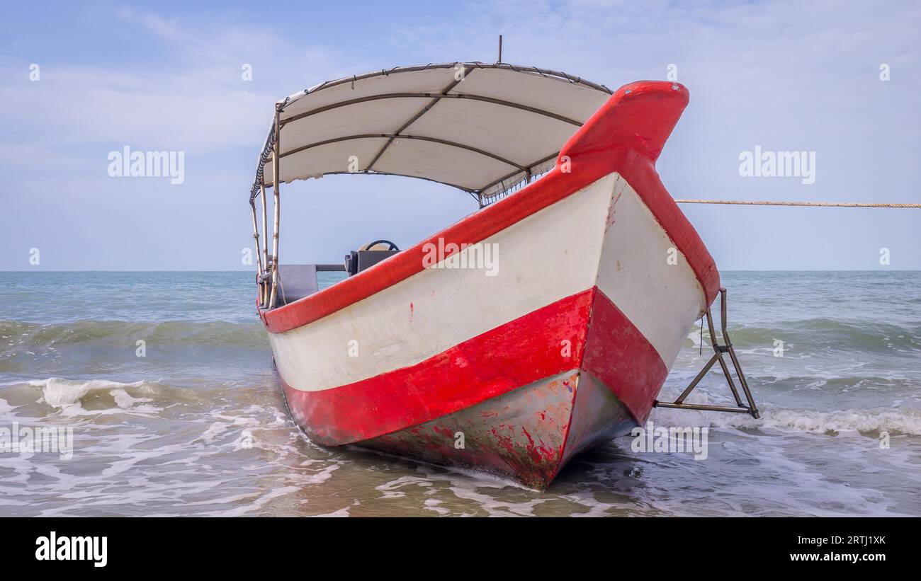 Longtail boat with red and white stripes waiting for passengers on beautiful monkey beach in Penang national park, Malaysia Stock Photo