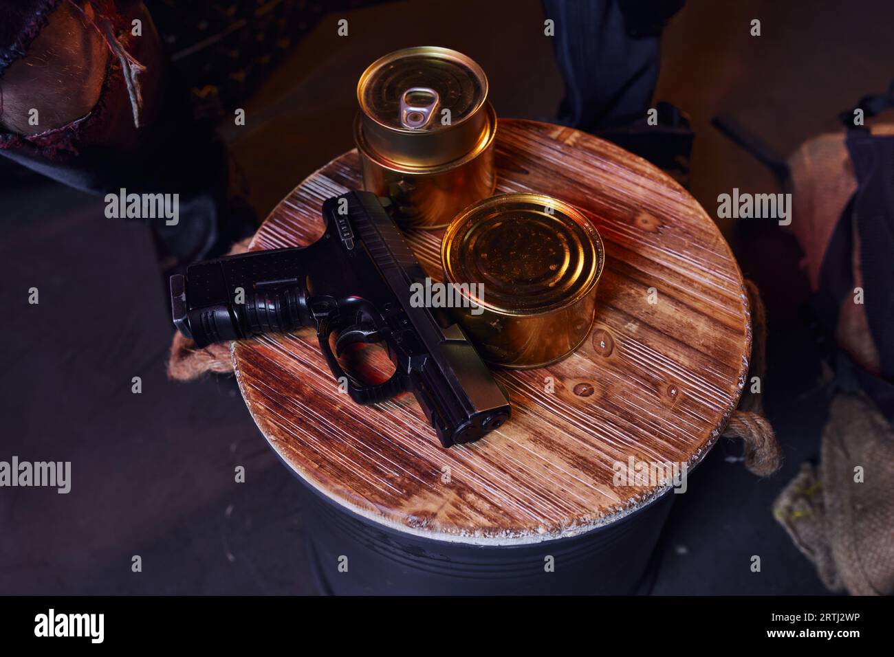 top view of gun and canned food near cropped man in underground, post-apocalyptic survival resources Stock Photo
