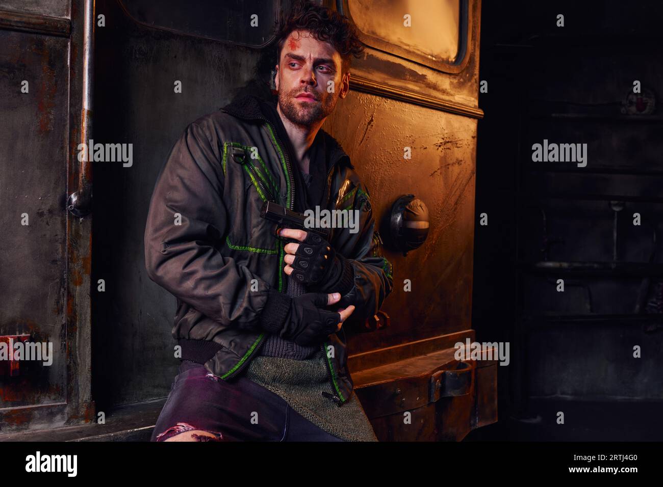 survived injured man holding gun and looking away in abandoned subway, post-apocalyptic concept Stock Photo