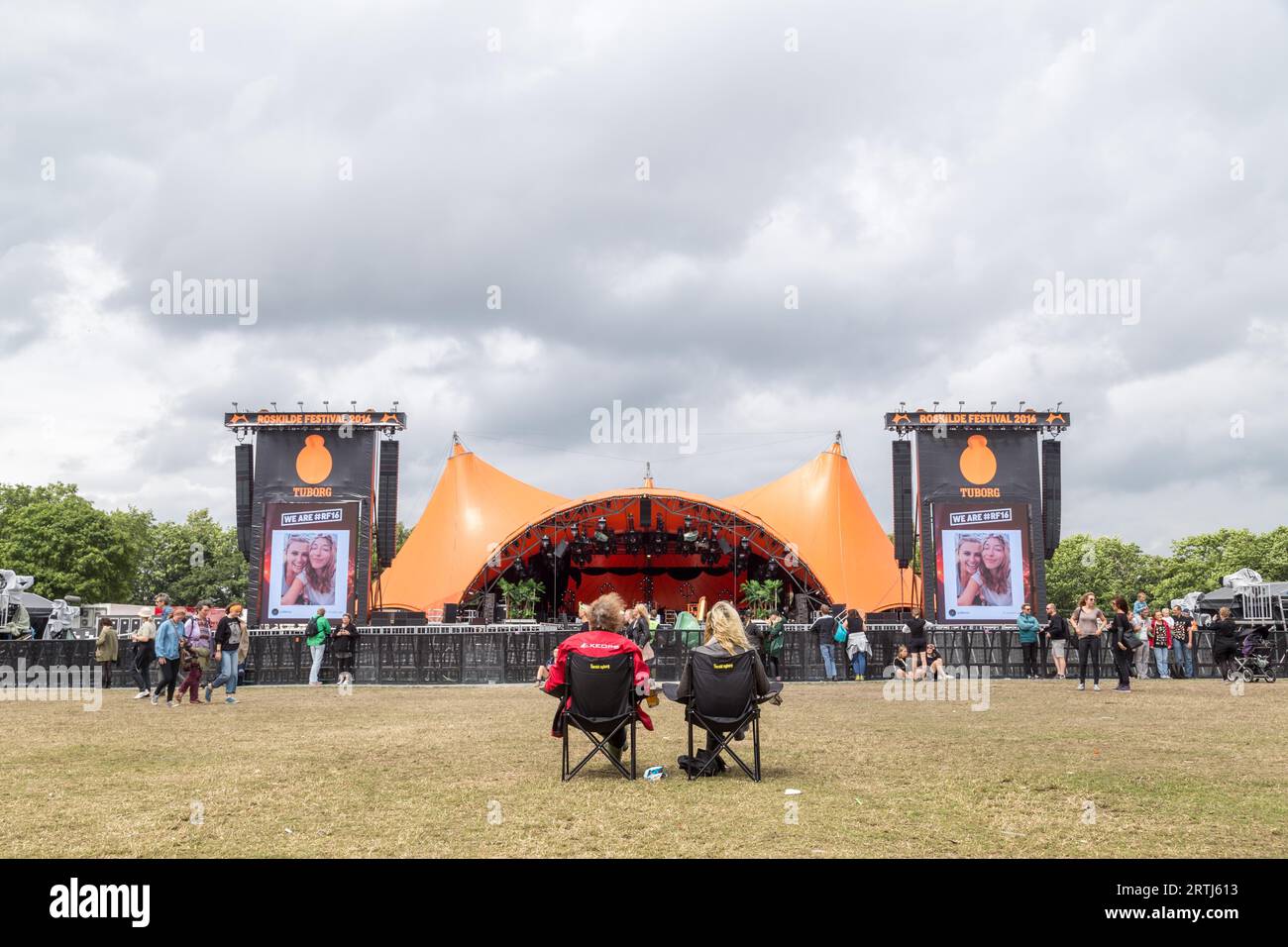 Roskilde, Denmark, July 1, 2016: Two people sitting in front of the orange stage at Roskilde Festival 2016 Stock Photo