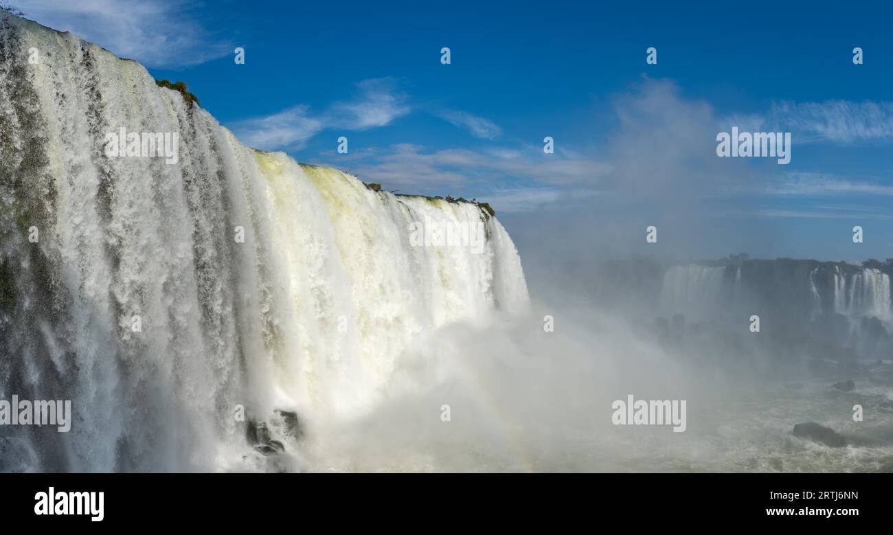 Close view of one of the Cataratas water falls under blue sky and a lot of water mist in the air at the Foz do Iguassu park, Brazil Stock Photo