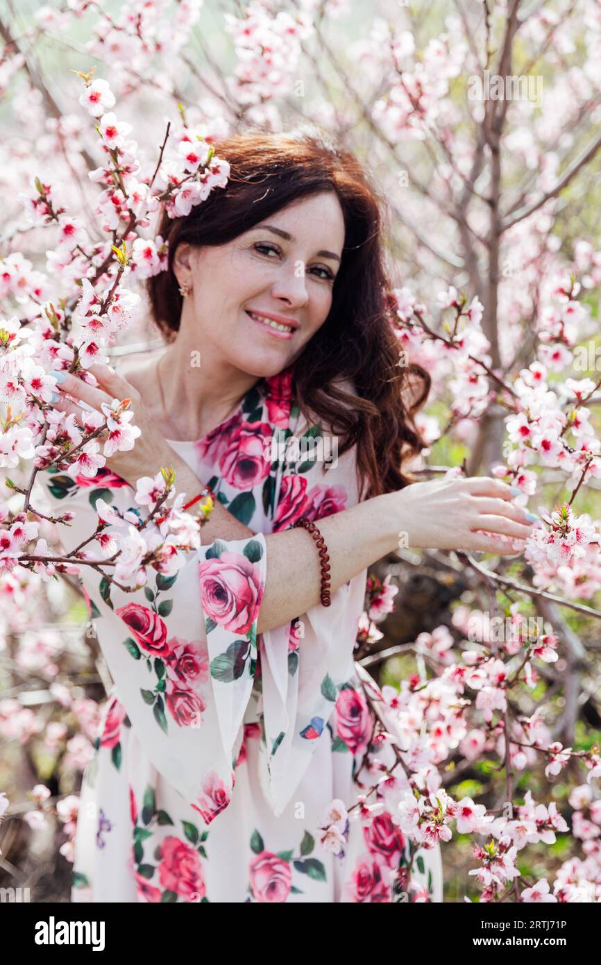 woman near pink flowering trees in peach garden nature spring Stock Photo