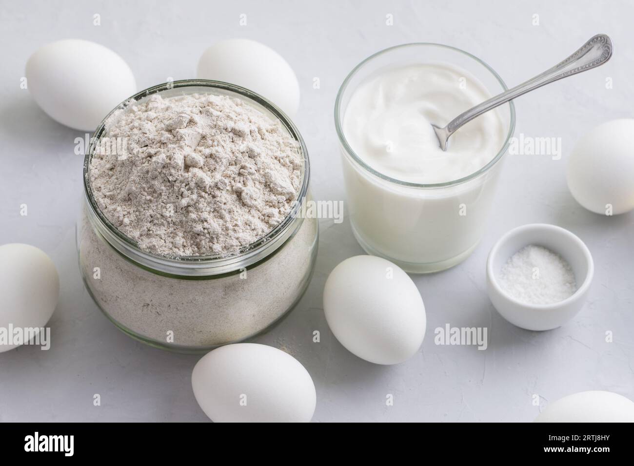 Ingredients for homemade rye pies with egg: rye flour, sour cream or yogurt and eggs on a light gray background, top view, selective focus Stock Photo