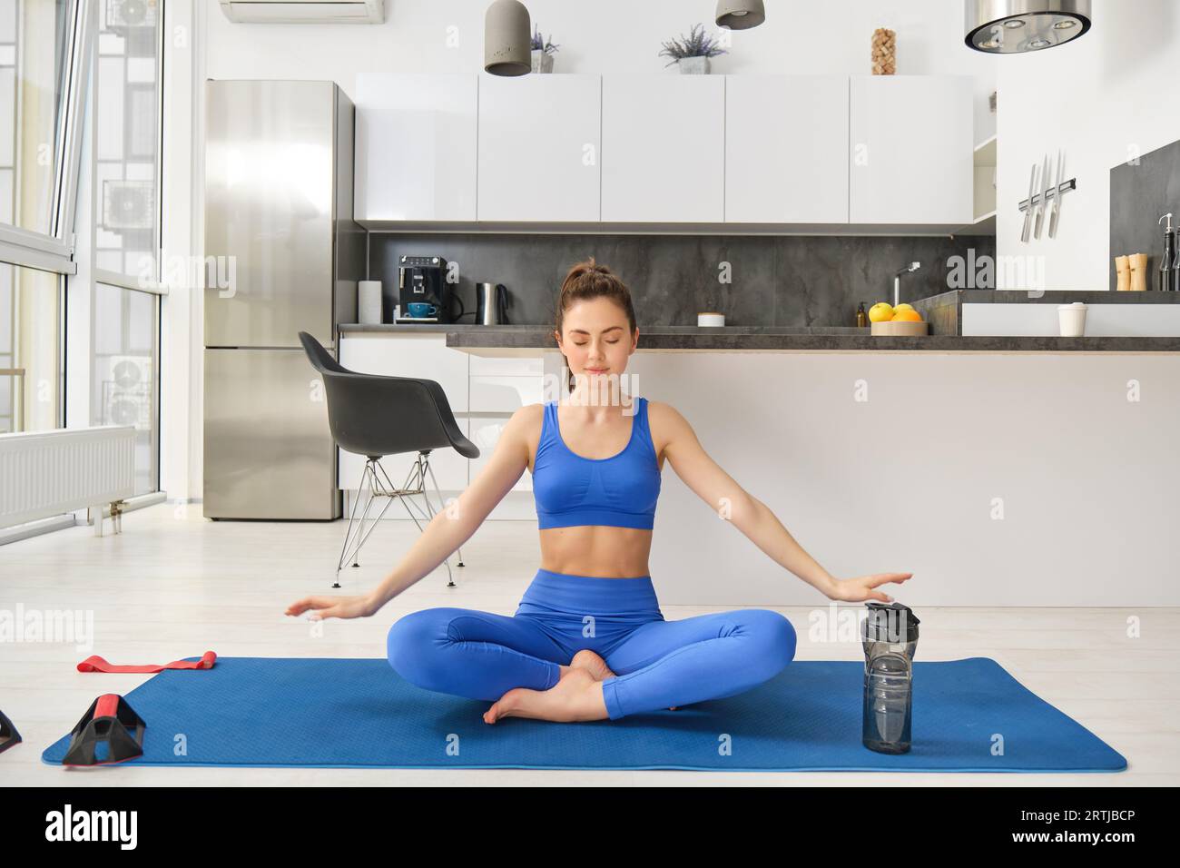 Happy and relaxed fitness girl, sitting on rubber mat doing yoga