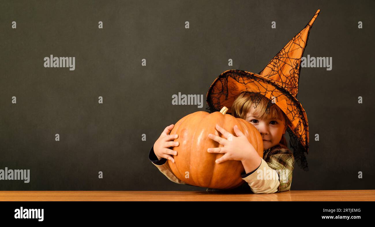 Preparation for Halloween holiday. Thanksgiving day cooking. Little child boy in witch hat with Halloween pumpkin. Halloween kid with jack-o-lantern Stock Photo