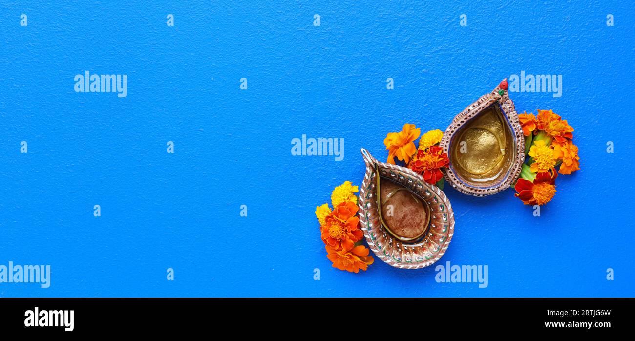 Diya lamps with marigold flowers on blue background with space for text. Divaly celebration Stock Photo