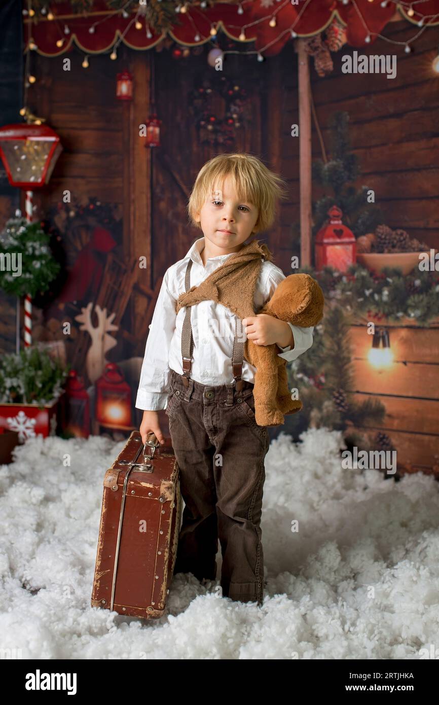 Cute fashion toddler boy, playing in the snow with teddy bear in front ...