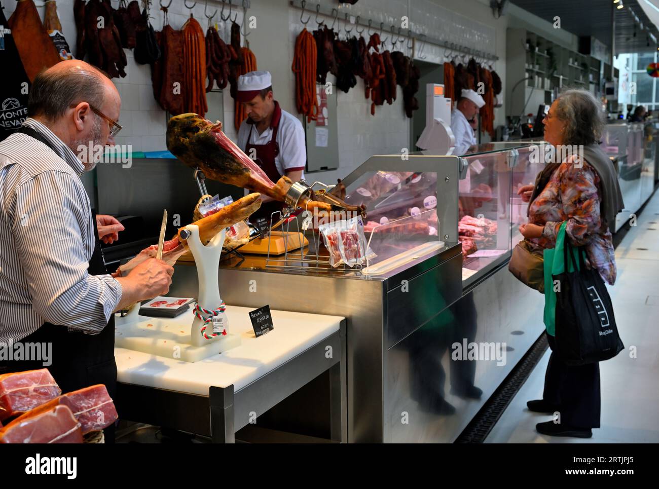 Butchers stall in covered market, Mercado do Bolhão, with ham hock being carved Stock Photo