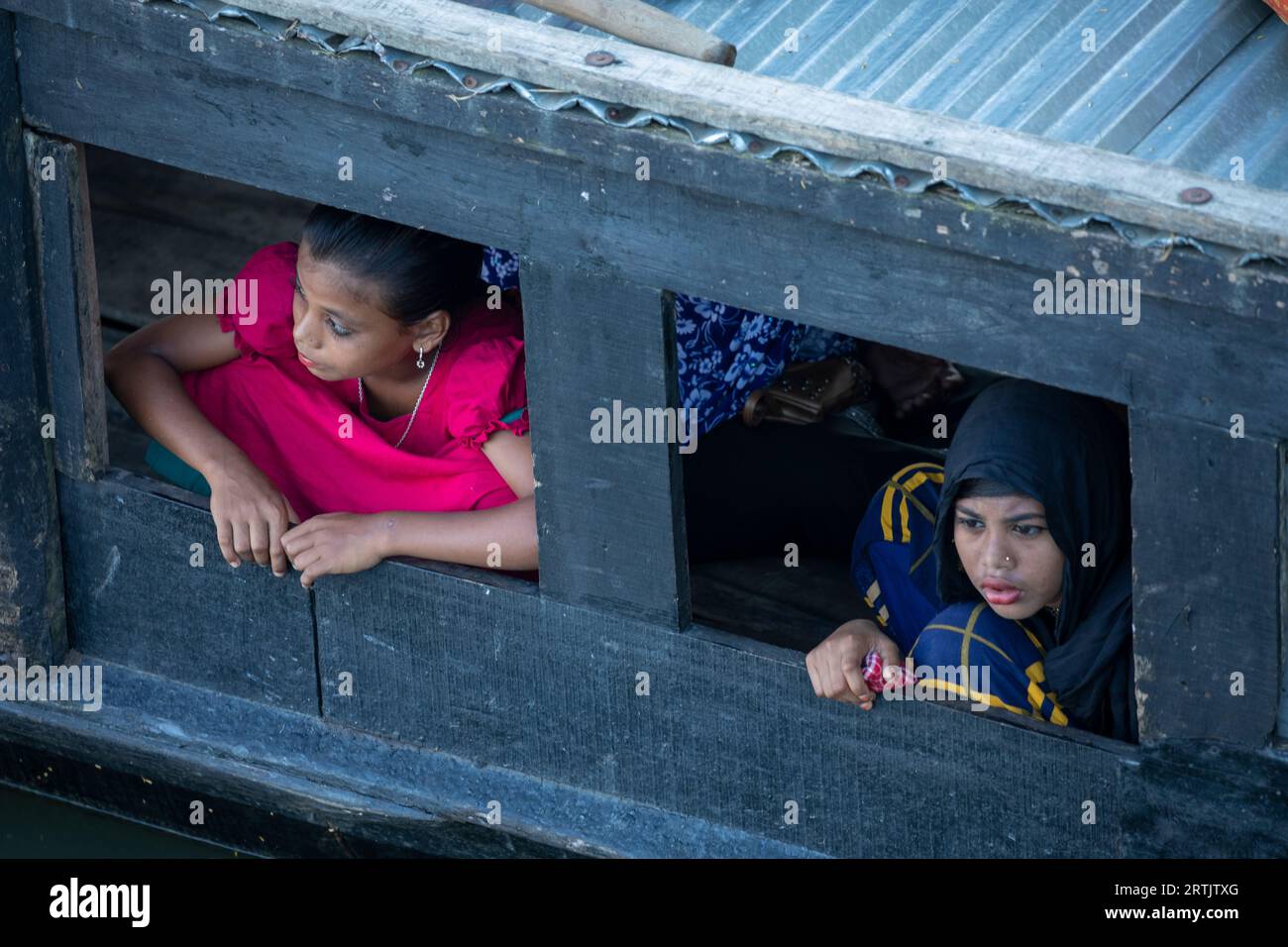 Rural girls look through a window of a boat at the Nikli Haor at austagram in Kishorganj. Bangladesh. Stock Photo