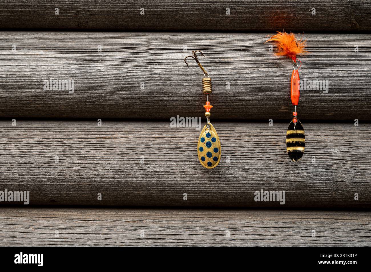 two red fishing lures hanging on a grey wooden wall Stock Photo