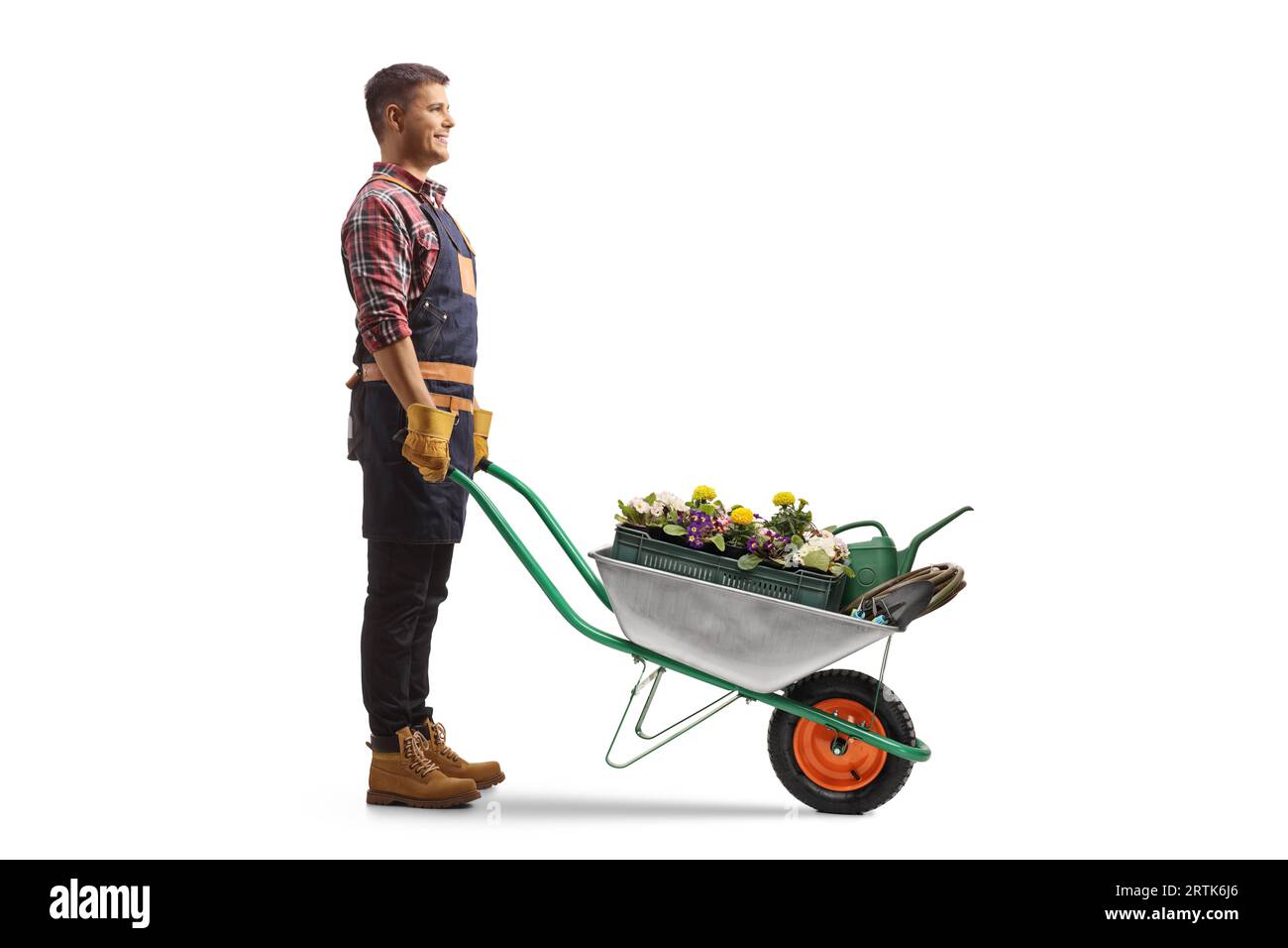 Full length profile shot of a gardener standing with a wheelbarrow full of flowers isolated on white background Stock Photo