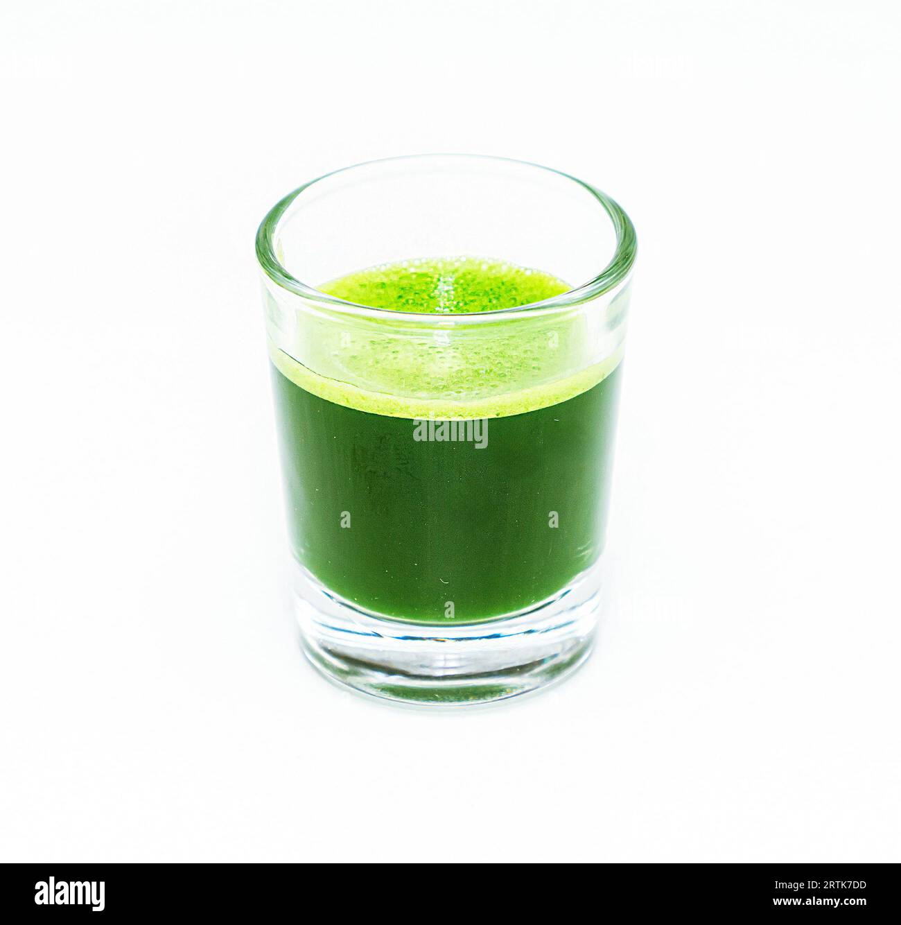 Healthy green wheat grass shot in small glass isolated on white Stock Photo