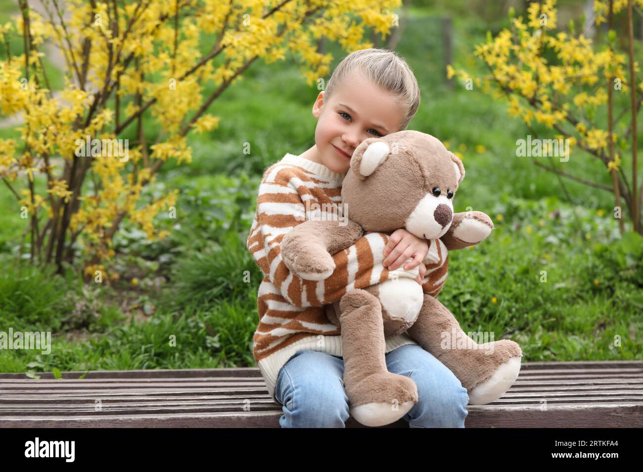 Little girl with teddy bear on wooden bench outdoors Stock Photo - Alamy