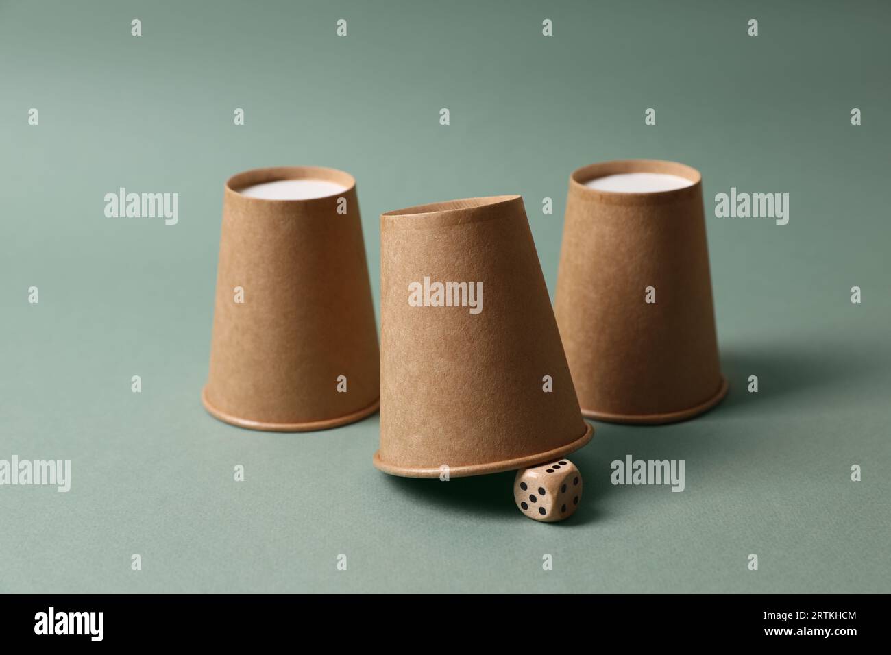 Three paper cups and dice on pale olive background. Thimblerig game ...