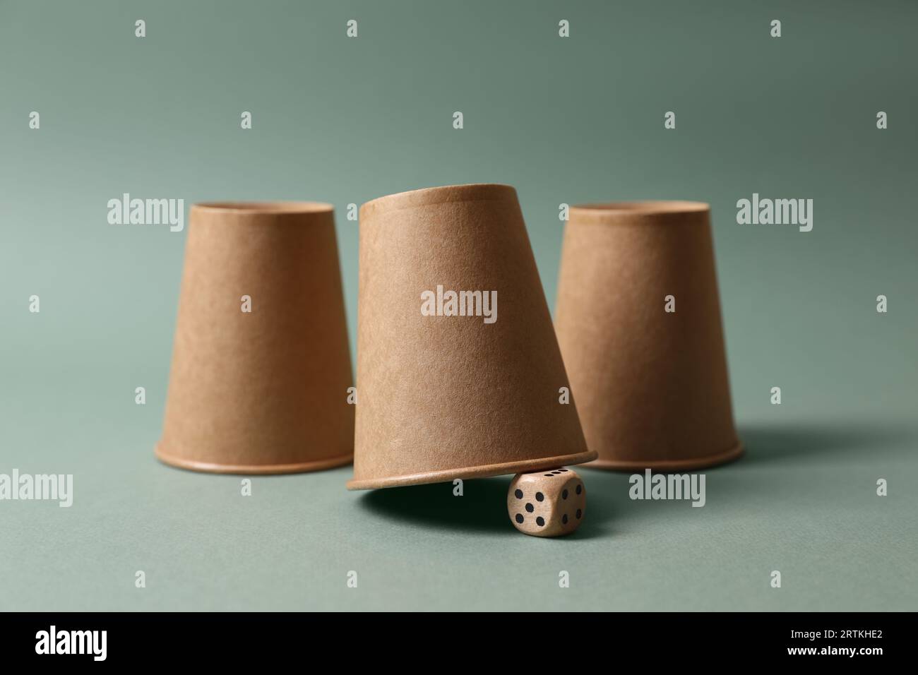 Three paper cups and dice on pale olive background. Thimblerig game ...