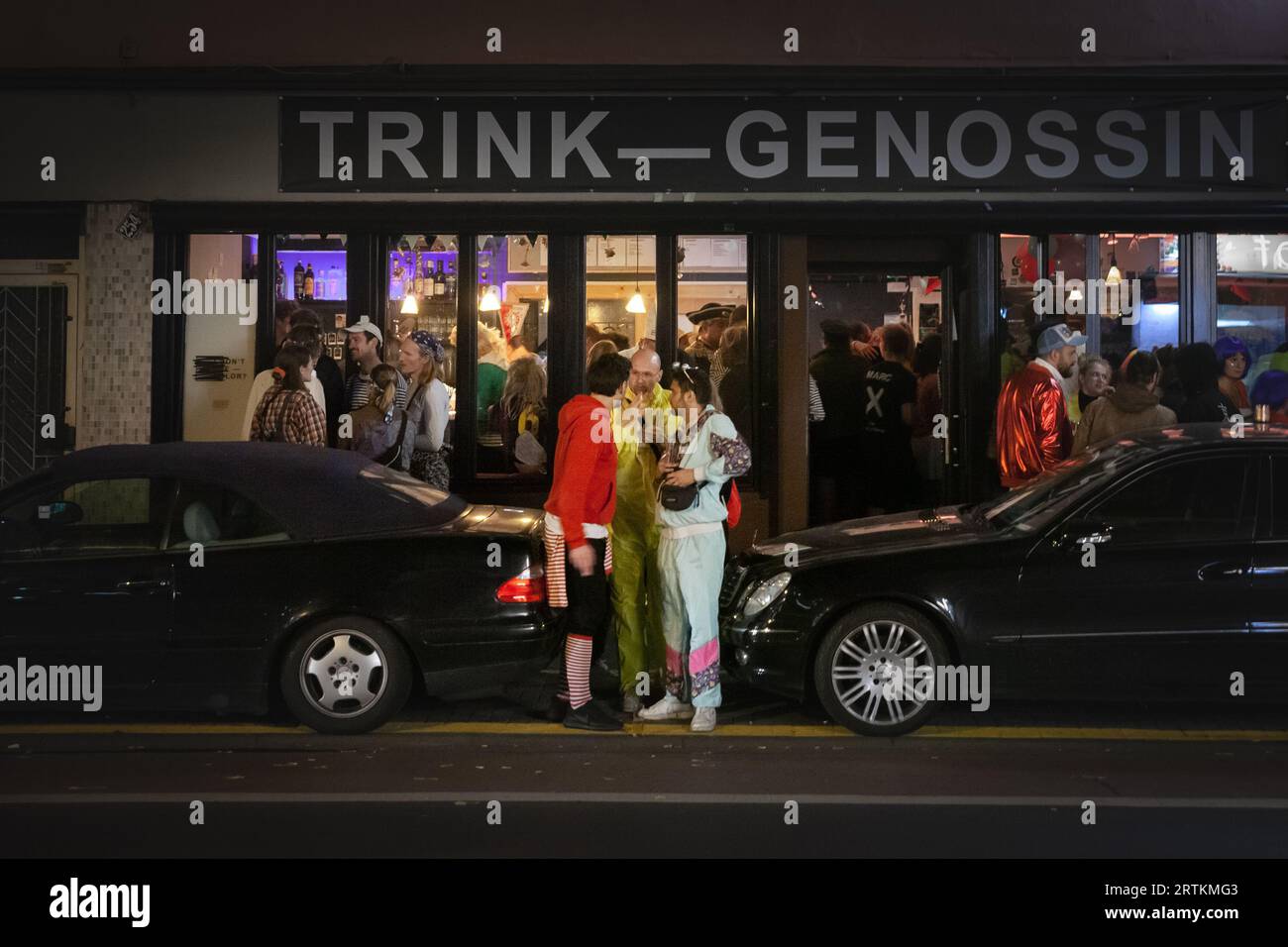 Picture of people dressed in costumes for Cologne Carnival drinking in the streets in front of a bar in Cologne, Germany. The Cologne Carnival (German Stock Photo