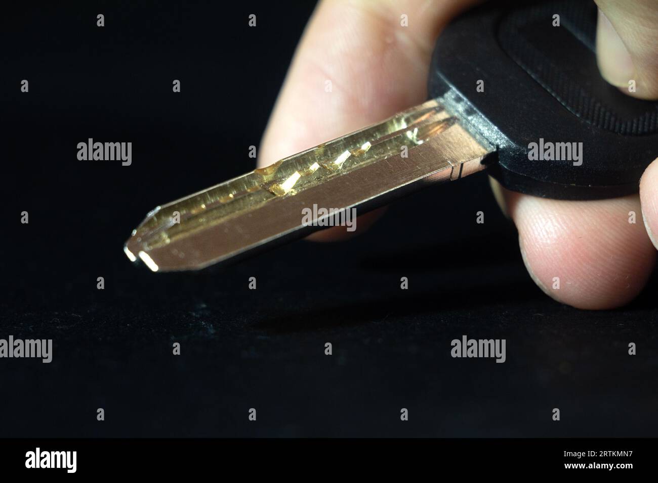 Picture of a dimple pin key isolated on black background, held by hands