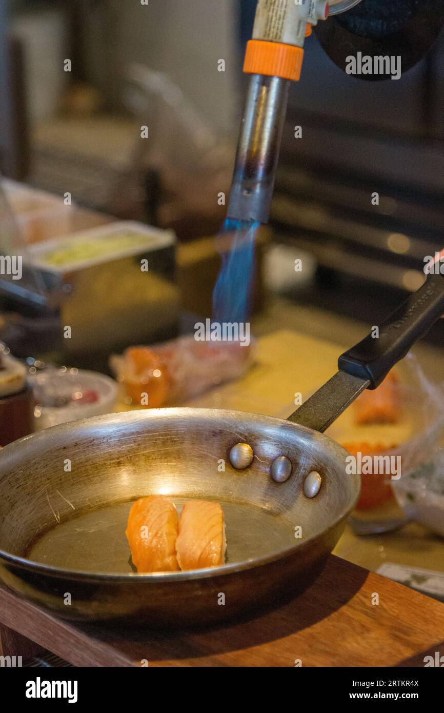 Searing a Pair of Salmon by the sushi chef Stock Photo