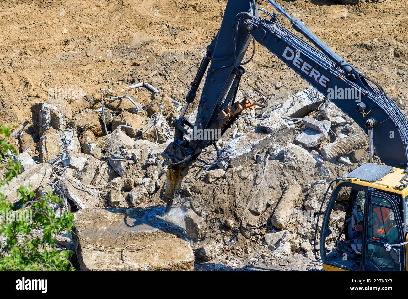 NEW ORLEANS, LA, USA - SEPTEMBER 13, 2023: John Deere excavator with a hydraulic hammer attachment breaks up a concrete slab at a demolition site Stock Photo