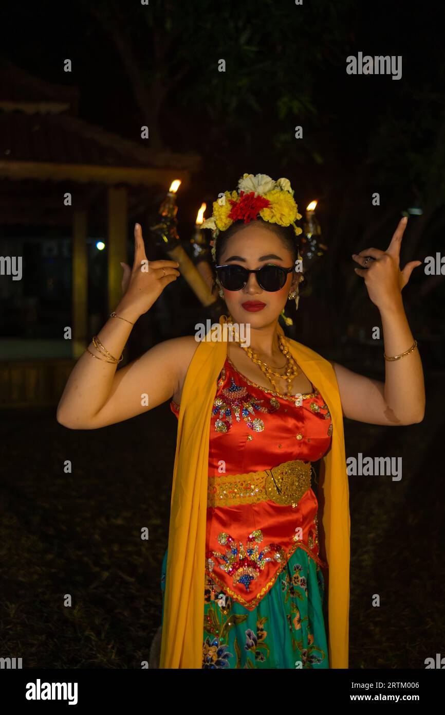 portrait of a traditional Javanese dancer dancing with very beautiful hand movements while wearing sunglasses at night Stock Photo