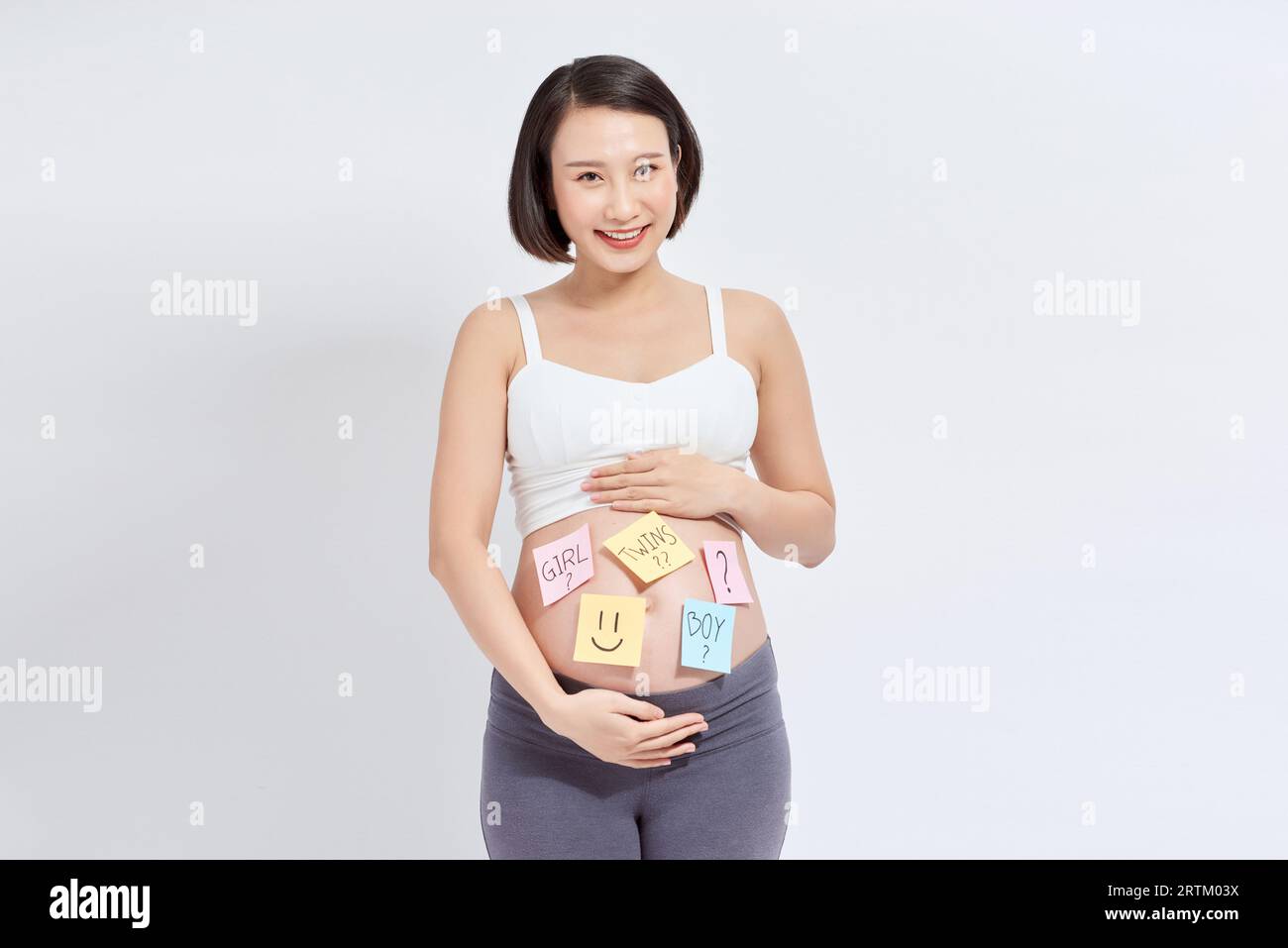 Choosing baby name. Confused pregnant woman with question marks on paper stickers on tummy Stock Photo