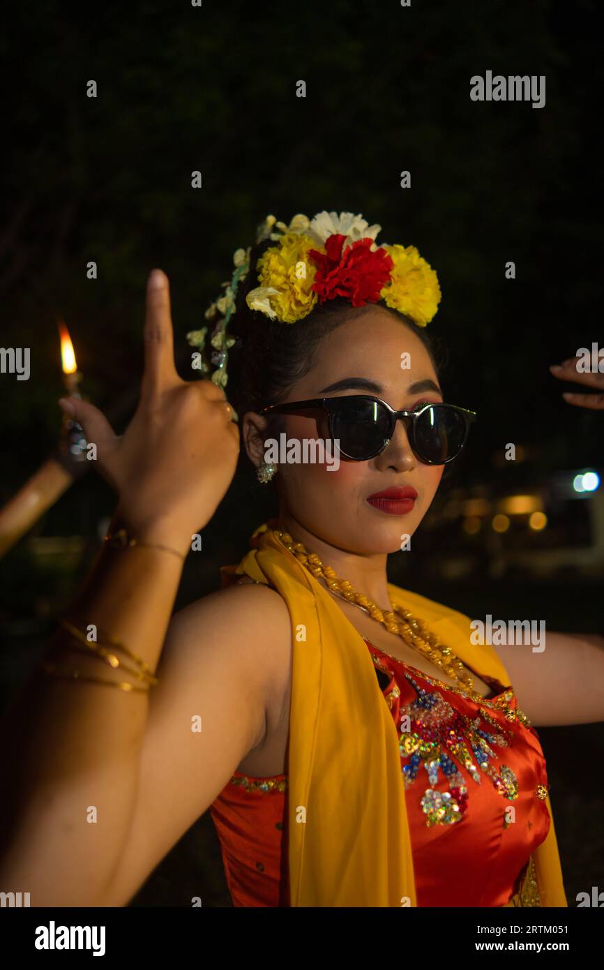 portrait of a traditional Javanese dancer dancing with very beautiful hand movements while wearing sunglasses at night Stock Photo