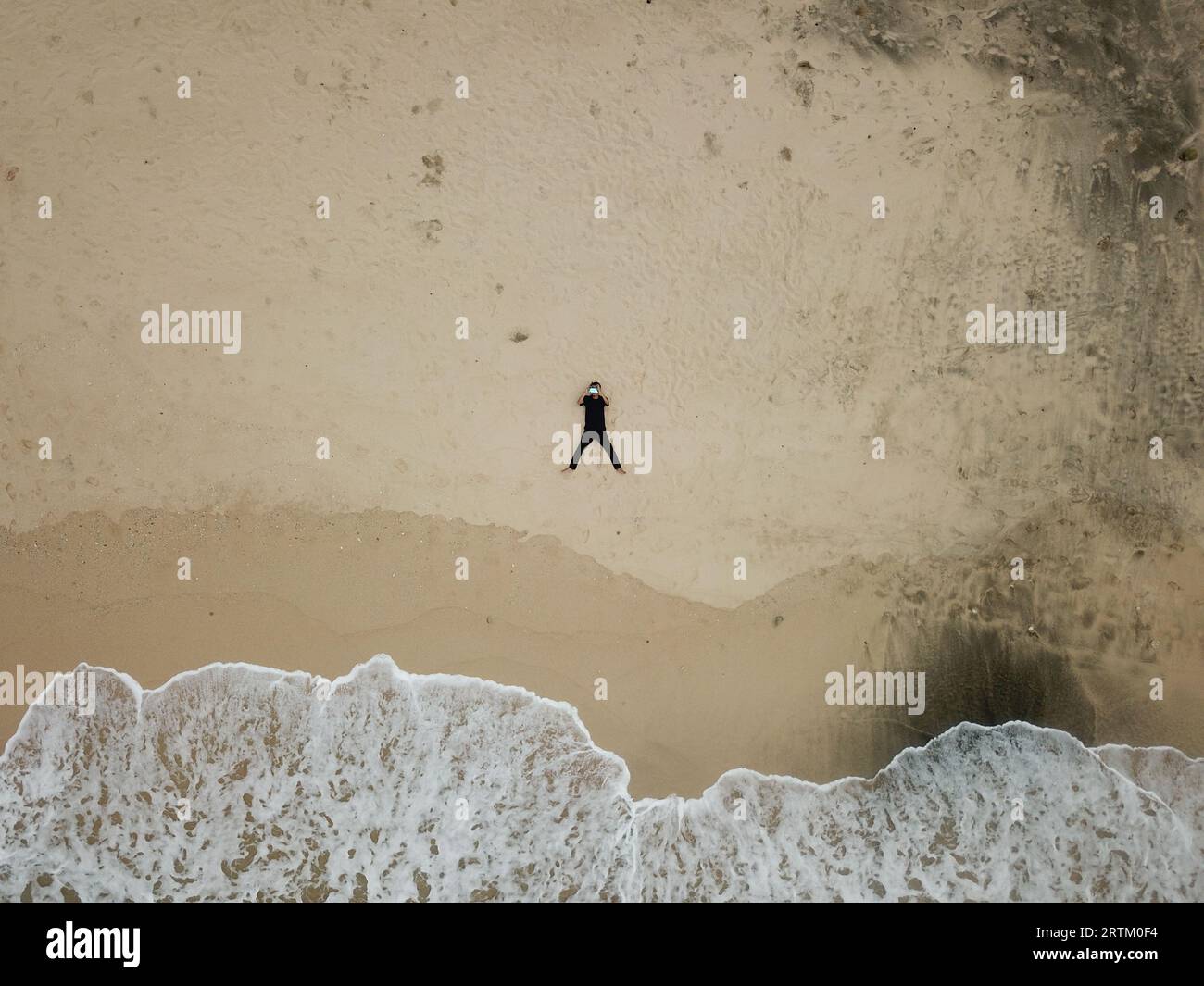 aerial view, a man lying on the shoreline and flying a drone Stock ...
