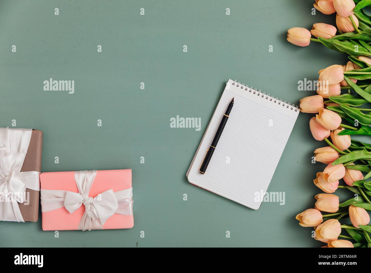 tulip flowers with gifts and notepad on blue as background Stock Photo ...