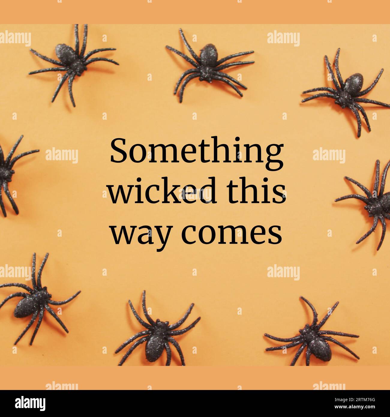Something wicked this way comes text with black halloween spiders on orange background Stock Photo
