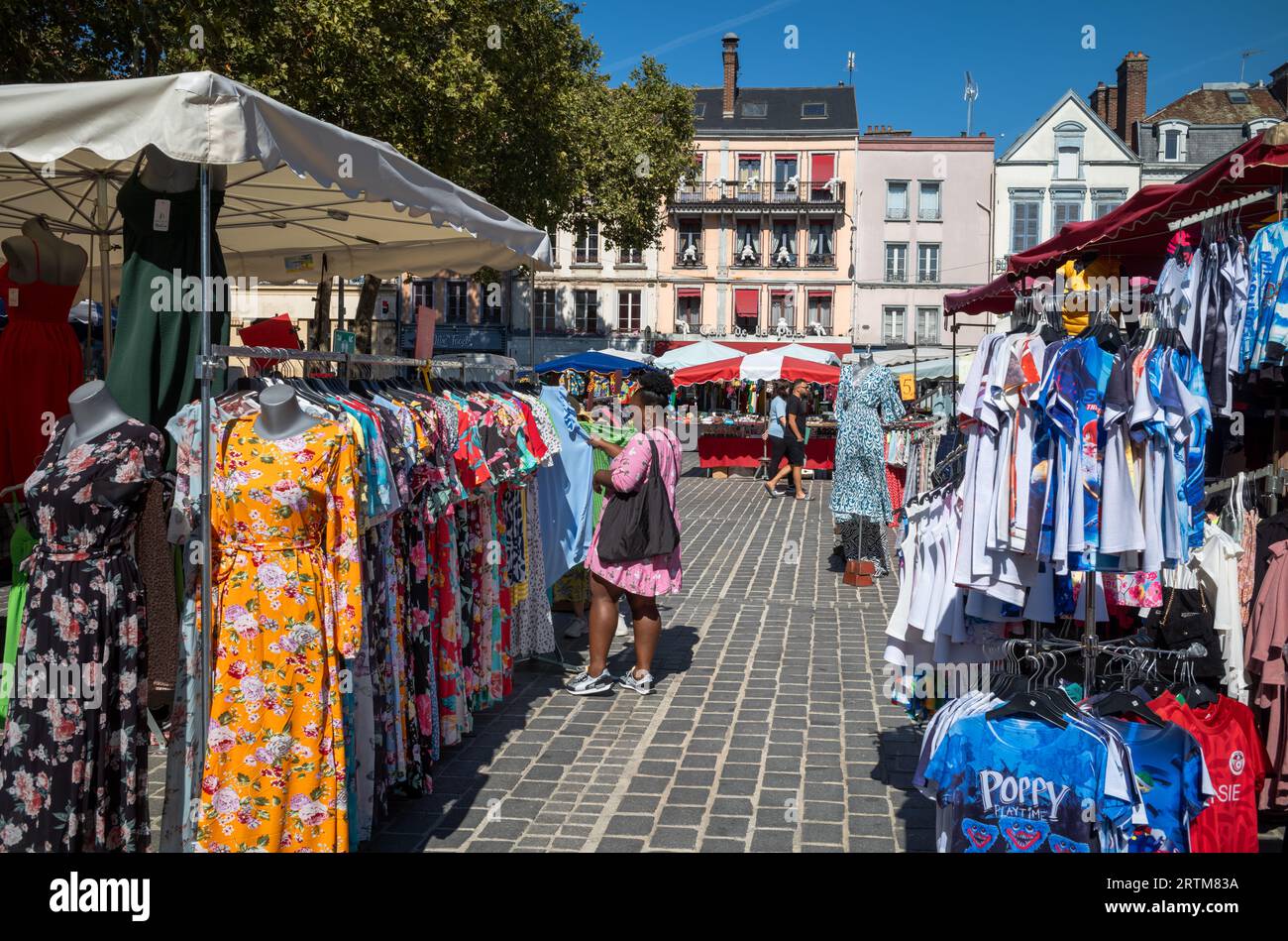 A woman of African origin browses clothing at a market stall outside the Central Market  (Marche des Halles) in Troyes, Aube, France. Stock Photo
