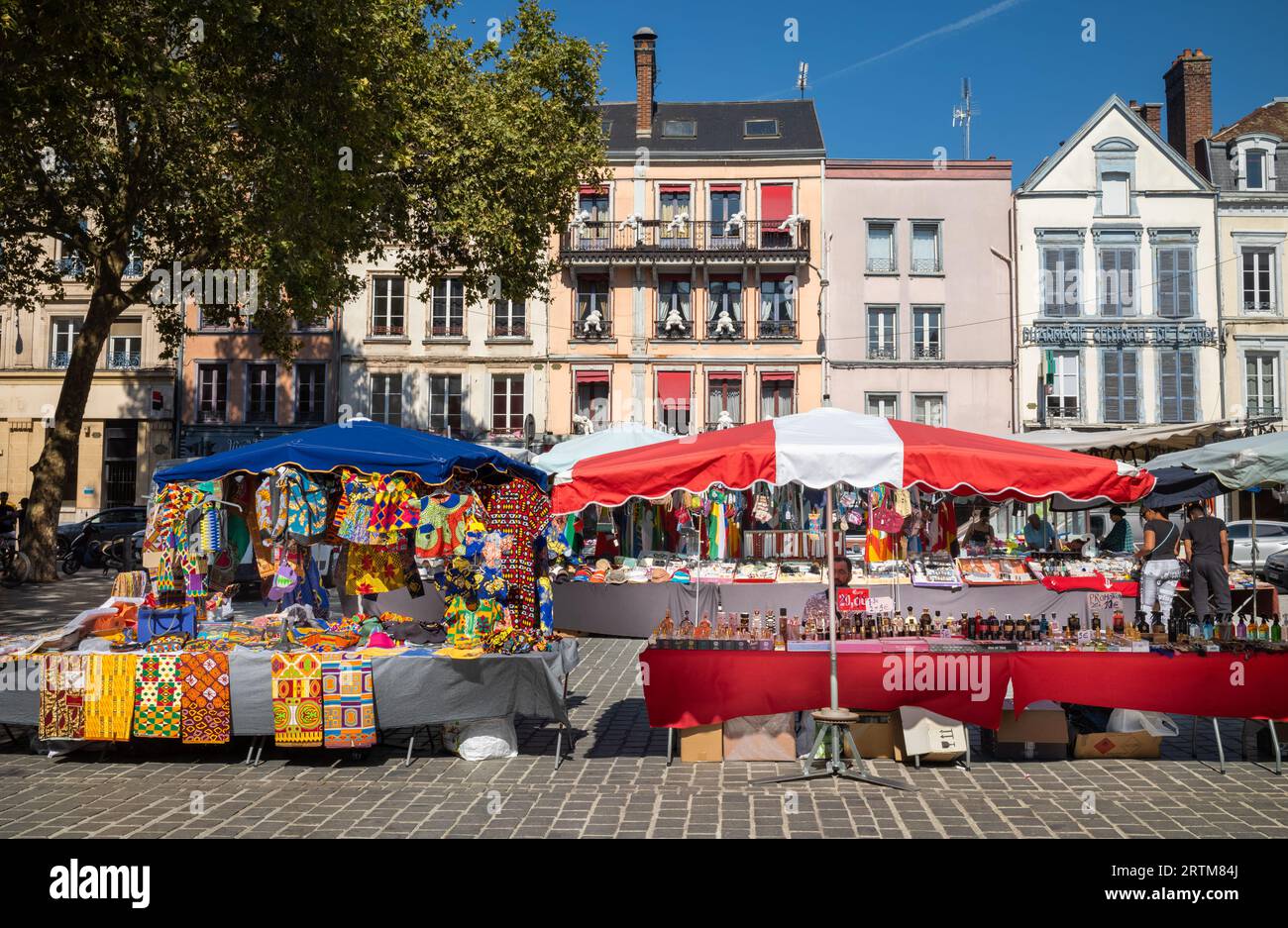 Traditional houses seen behind colourful African-style clothing for sale next to a perfume stall outside the Central Market  (Marche des Halles) in Tr Stock Photo