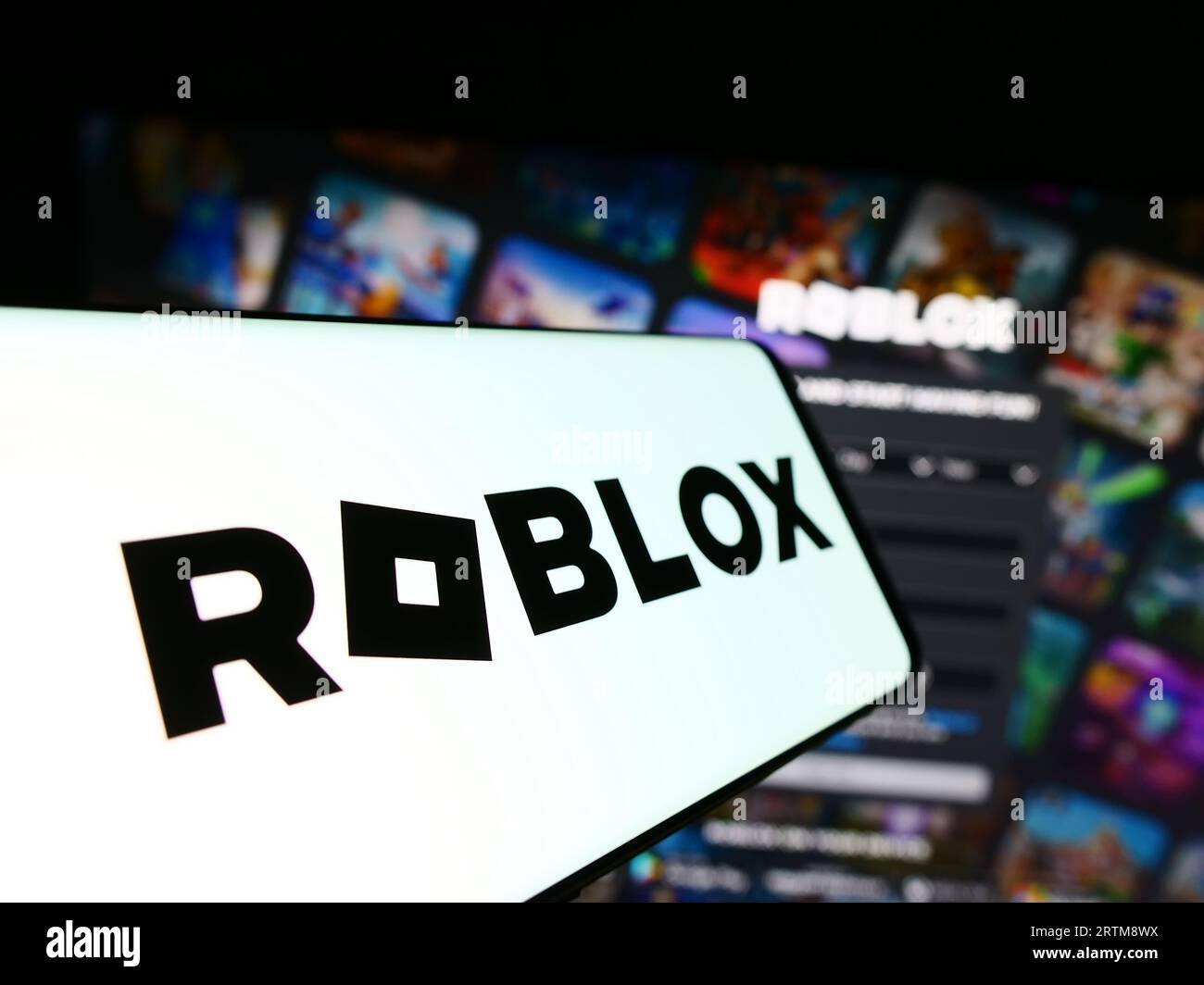 Cellphone with logo of American video games company Roblox Corporation on screen in front of website. Focus on center-left of phone display. Stock Photo