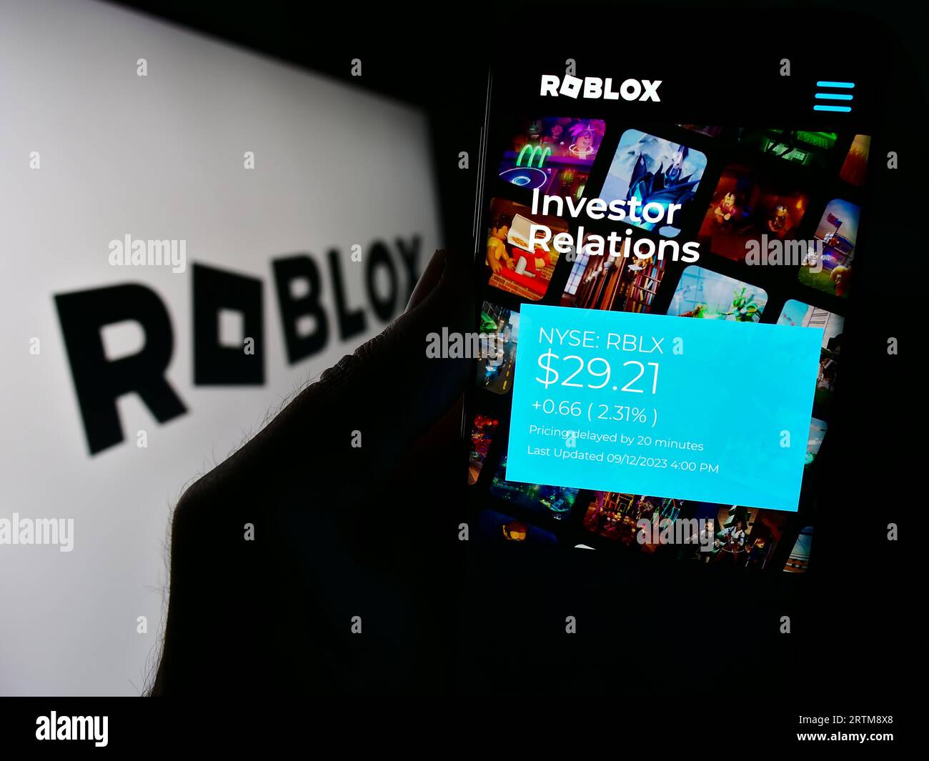 Person holding smartphone with website of US video games company Roblox Corporation on screen in front of logo. Focus on center of phone display. Stock Photo